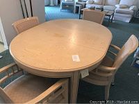 Oval light wood dining table with four matching chairs in room setting, showing marks and wear on table surface.