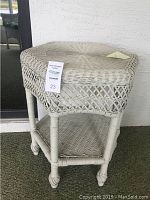 Full view of the wicker end table showing woven wicker design, legs, and lower shelf.