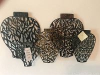 Overview image of four different sized metal wall decor panels arranged against a wall.