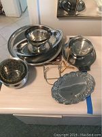 Full set of 9 stainless steel serving dishes on table showing varied sizes and shapes