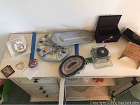 Top view of all nine pieces displayed on beige tabletop showing music box, geode, jewelry box, candle wreath and other decor items