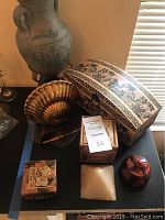 Photo showing all nine items arranged on a black surface, including large vase, decorative box, shell-shaped dish, and smaller containers.