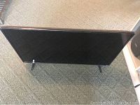 Vizio 39 inch TV standing on carpet with visible TV screen and legs.