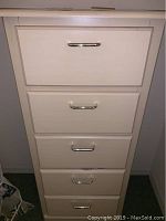 Front view of white chest of drawers showing five drawers with metal handles.