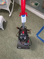 Front view of Hoover Nano Cyclone vacuum cleaner showing the base, handle, and wrapped power cord.