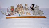 Front view of 13 cat figurines showing diversity of styles including Willow Tree angel, Quarry Critters, Kitty's Kennel figurine, small miniatures, and two cats with removable tops.