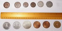 All 12 coins and medals arranged in two rows on a white background with a ruler for scale, showing front sides.