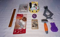 Photo showing entire lot with the leash, toys, grooming tools, planter, notebook and ruler for scale on white background.