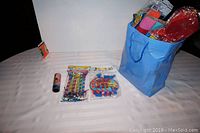 View of all items including the blue bag with streamers, party blowers pack, confetti canister, and sparkler candles on a white surface.