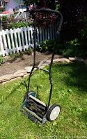 Full view of the Yardworks 14-inch reel mower in grass with handle upright.