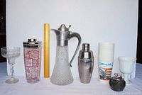 Full lot photo showing Italian decanter, two cocktail shakers, Gremlins movie cups, two cocktail glasses.