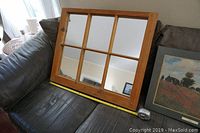 Old wooden window frame mirror with six glass panes on a couch showing size with tape measure approximately 24 by 29 inches.