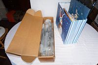 Overall view of cardboard box containing rolled Space Saver bags and a decorated gift bag filled with various gift bags including kids goody boxes.