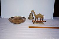 Front view of brass bowl and camel bell set with ruler for scale
