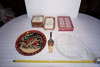 Photo shows entire Christmas serving lot with ceramic cake plate and knife, glass serving plate, paper napkins, and ceramic napkin rings all arranged on table