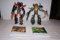 Two assembled Lego Hero Factory figures Rocka XL and Fire Lord with their respective original instruction booklets placed in front of them on a table.
