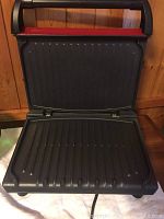 Open view of the George Foreman grill showing both upper and lower ridged grill plates and handle