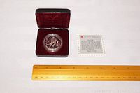 Front view of the Stanley Cup Centennial 1993 Canadian Silver Dollar coin in a protective plastic casing displayed inside a burgundy velvet-lined presentation case with certificate and ruler for scale.