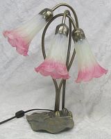 Full view of table lamp showing three lily-shaped glass shades in pink and white gradient on bronze-tone metal base shaped like lily pads.