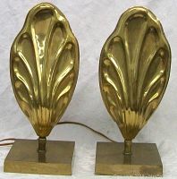 Pair of brass fan-shaped lamps shown unlit from front view on a white fabric backdrop.