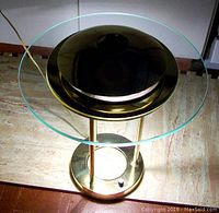 Top-down view of the brass and glass table lamp showing circular clear glass top and brass base with dimmer switch.