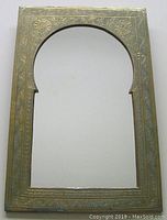 Front view of Moroccan-style decorative mirror showing arched floral-engraved metal frame