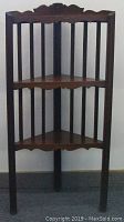 Full front view of the antique Gothic wooden corner shelf showing two triangular shelves and vertical slats.