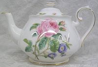 Front side view of the Royal Albert Roses teapot showing detailed rose and morning glory floral patterns, white porcelain body with gold trim.