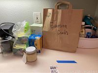 View of assorted household cleaning and hardware items including sponges, a brown paper bag labeled 'Extension Cords', and packaged items on a counter.