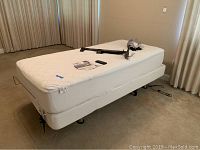 White twin size electronic adjustable bed with mattress and metal guard rail detail.