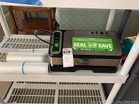 FoodSaver vacuum sealer machine on plastic shelving with vacuum seal bags and rolls next to it.