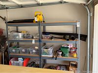 Photo showing two assembled metal shelving racks in a garage area with some plastic bins and miscellaneous items stored on them.