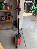 Full view of Black and Decker Edge Hog electric edge trimmer in upright position against wall showing handle and wheels.