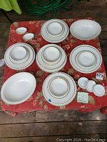 Overview of the set on a table showing multiple plates, bowls, and serving dishes with gold rims.