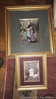 Framed print showing a girl outdoors in a dress holding object, gold frame, green matting