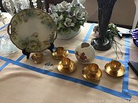 Image showing the set of four gold-tone Japanese tea cups with matching saucers, the footed Japanese vase with hummingbird, and the hand-painted Bavarian plate with floral design on display.