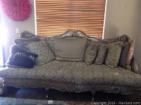 Front view of the Plunkett branded couch showing ornate carved wood framing and upholstery.