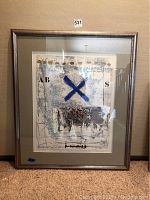 Framed signed abstract art piece with a blue X and mixed media elements inside frame.