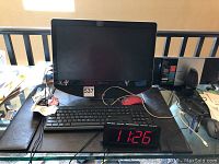Gateway 20-inch monitor with black wired keyboard on desk alongside digital alarm clock showing 11:26.