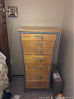 Front view of wooden jewelry armoire cabinet showing seven drawers and metal handles, minor surface scratches visible.