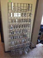 Front view of full metal display rack showing grid surface with multiple hooks including long straight hooks and wave-shaped hooks.