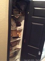 Closet shelves with folded king-size sheets and blankets in earth tones, some patterned including leopard print