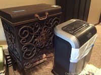 Photo shows the paper shredder and metal filing cabinet side by side on carpeted floor.