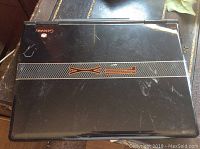 Top view of closed black Gateway laptop with orange FX logo, showing scratches and wear
