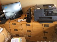 Light wood six drawer dresser with electronics on top and wires hanging down
