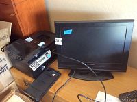 Emerson 19 inch TV and HP Officejet 4500 printer positioned side by side on wooden surface, showing front and side views.