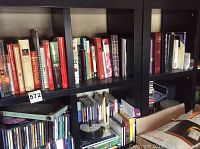 Shelf full of mixed books including religious texts and dictionaries, with visible spines showing some titles.