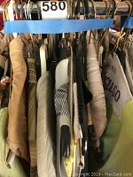 Photo of several knitwear pieces on hangers showing different neutral colors and textures