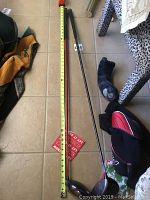 Full-length photo showing one golf club next to tape measure showing about 45 inches long, with other items around it.