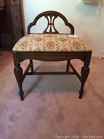 Front view of the stool showing curved mahogany backrest, fluted legs, and floral upholstery.